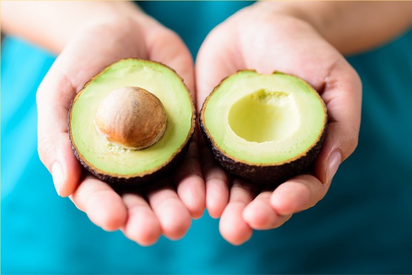 Persona tomando con sus manos un aguacate.