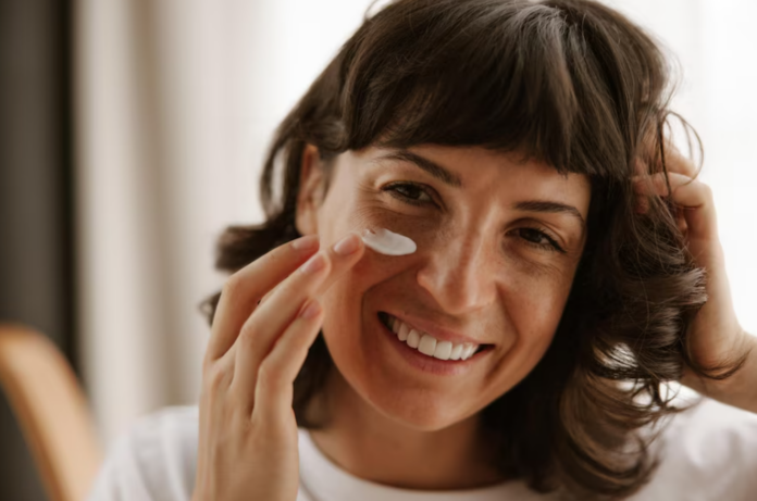 Mujer colocándose crema en la cara.